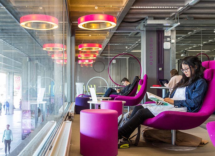 A young woman sits in the UCD Library reading.
